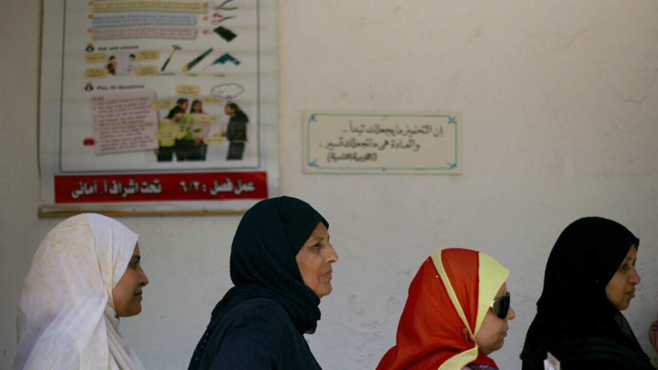 Women wait to vote at a polling station