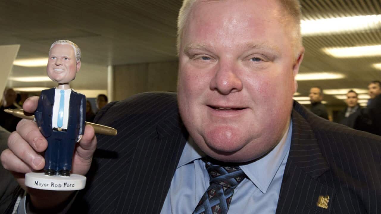 Toronto Mayor Rob Ford poses with a bobblehead doll in his likeness