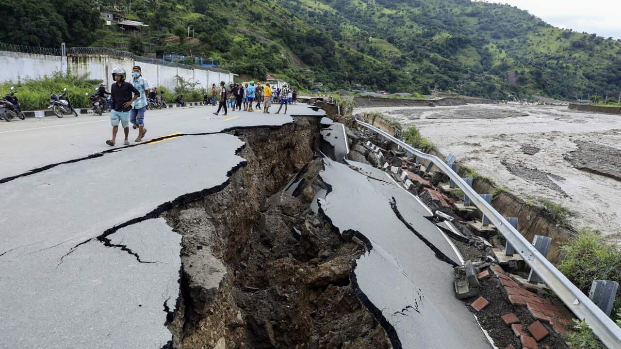 Officials inspect a damaged road in the aftermath of floods in Dili, Timor Leste