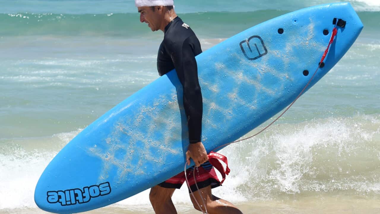 A surfer carries his board