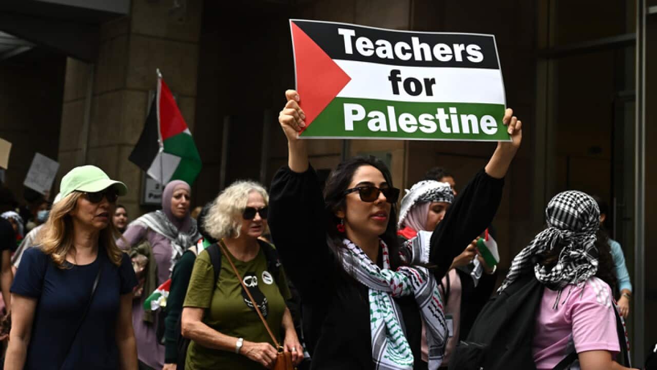 A woman holding aloft a Teachers for Palestine banner