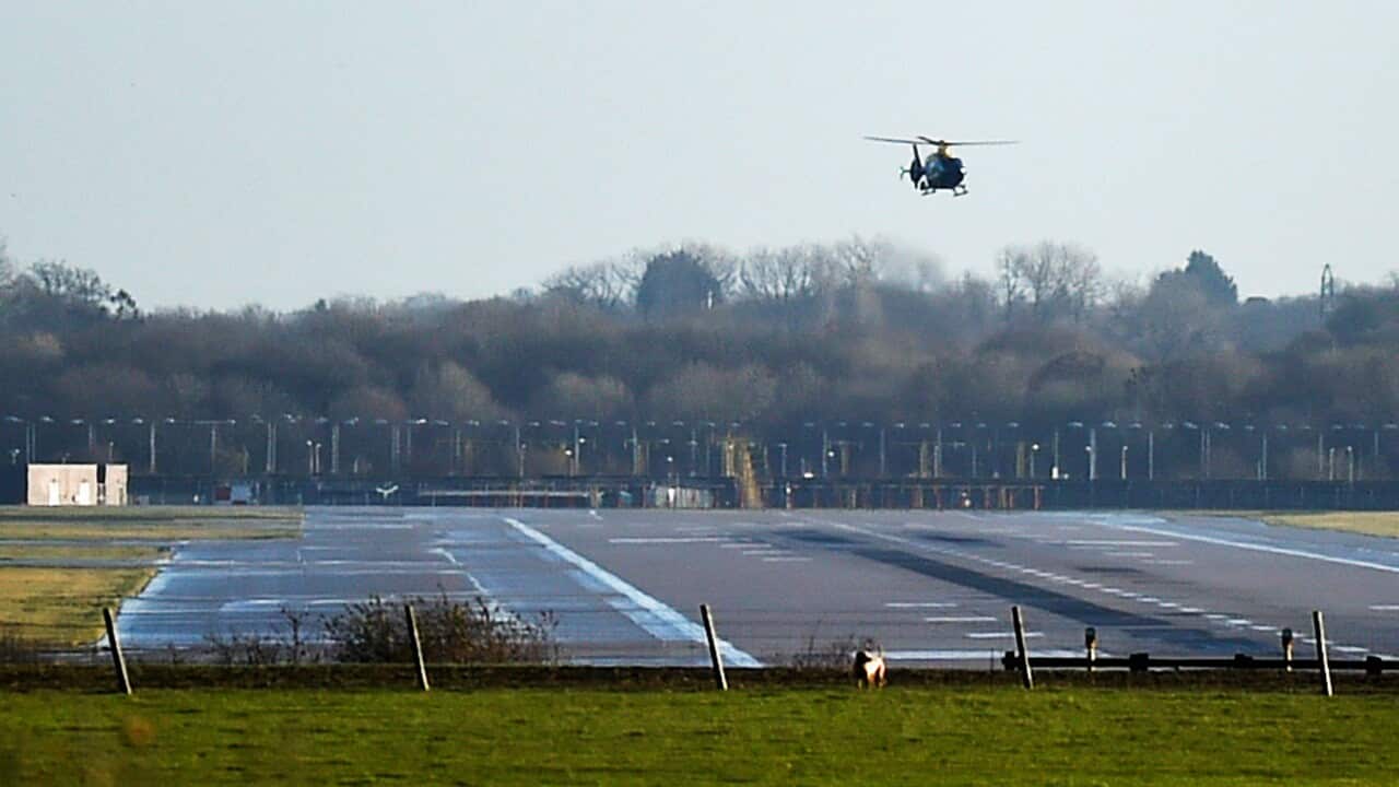 A police helicopter flies over the runway at Gatwick airport.