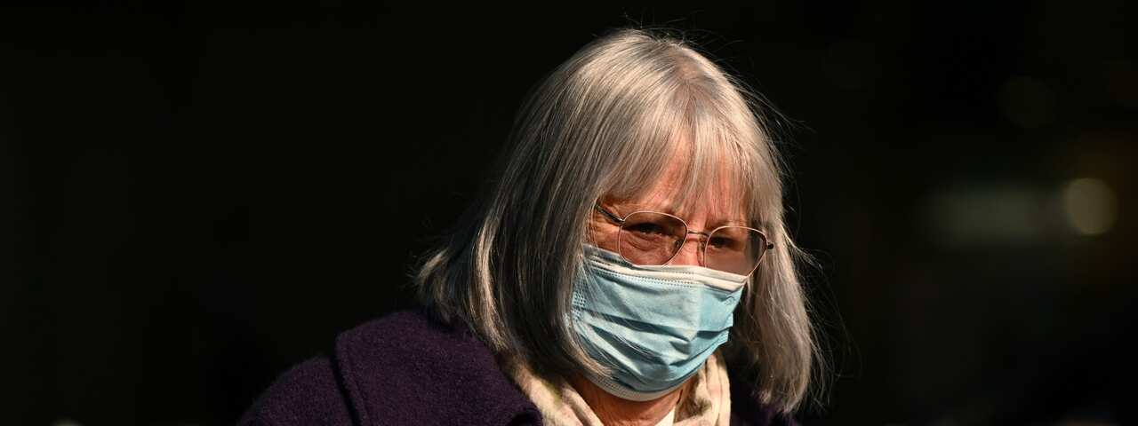 An older woman wearing face mask walking through Melbourne