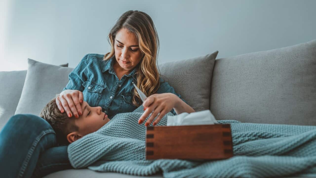 Mother checking temperature of her sick son who has thermometer