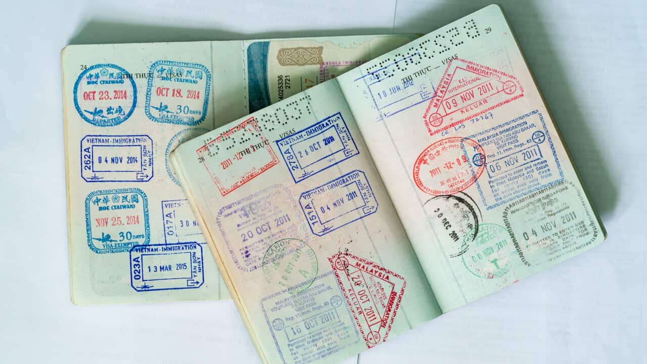 Two passports spread open, showing numerous stamps on the pages inside.