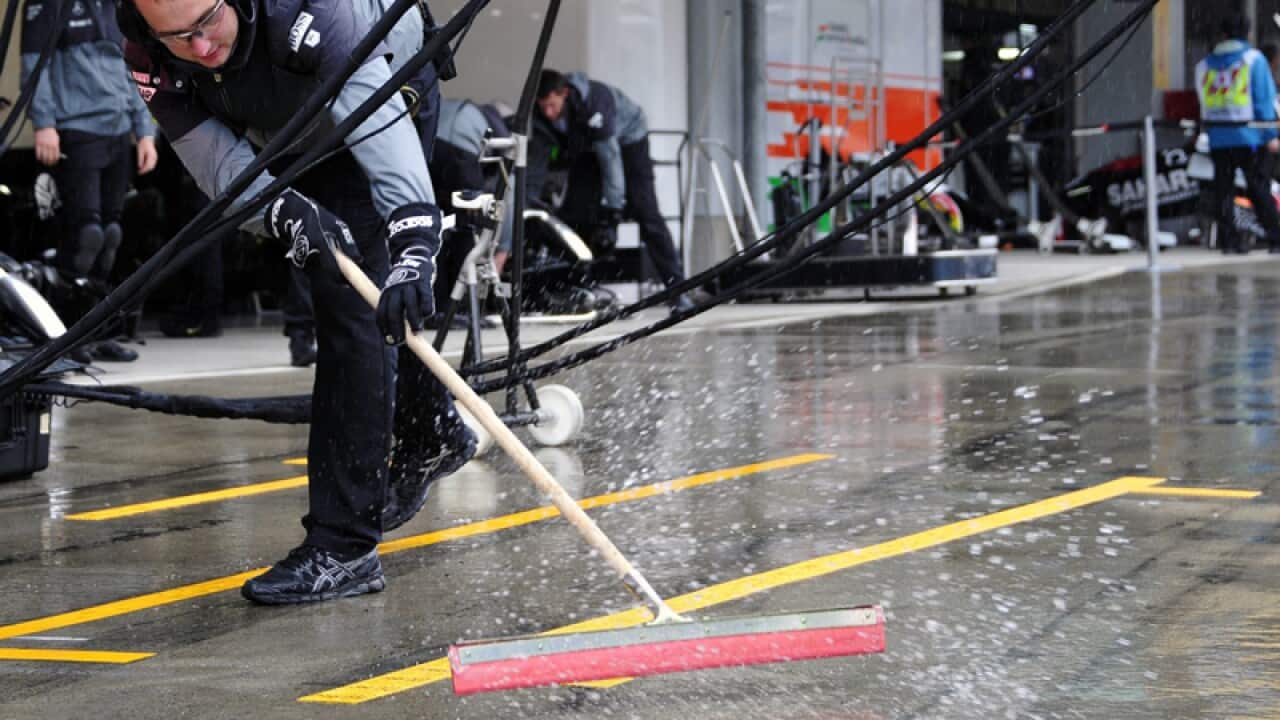 A mechanic of McLaren Mercedes wipes water from the pit