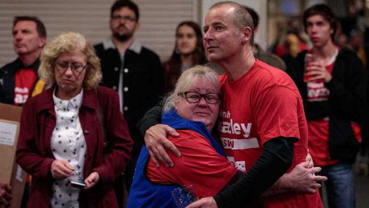 Devastated Labor volunteers watch on as the election result plays out on television.