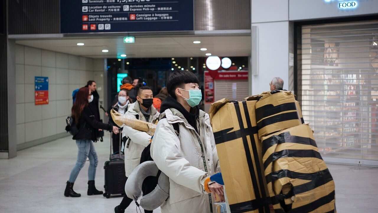 Travelers coming from Beijing and wearing a mask arrive at Charles de Gaulle airport in Paris.