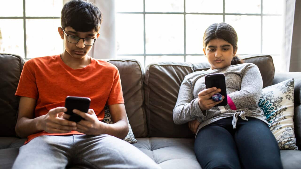 Brother and sister using smartphones at home