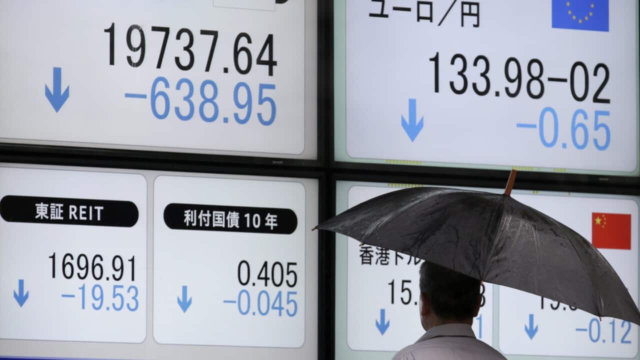 A Tokyo businessman is watching a display showing closing information of Tokyo's Nikkei Stock Average.