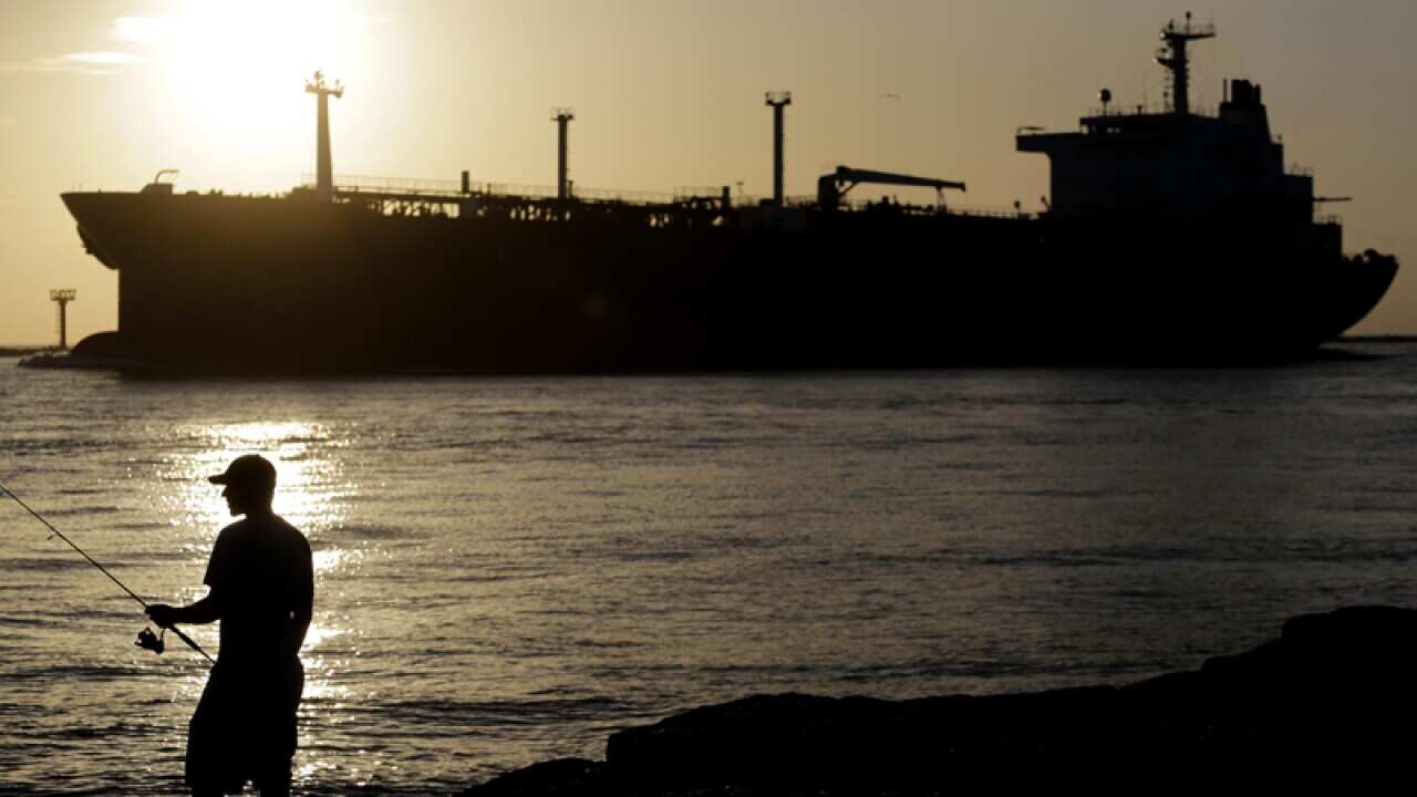 An oil tanker passes a fisherman near Port Aransas
