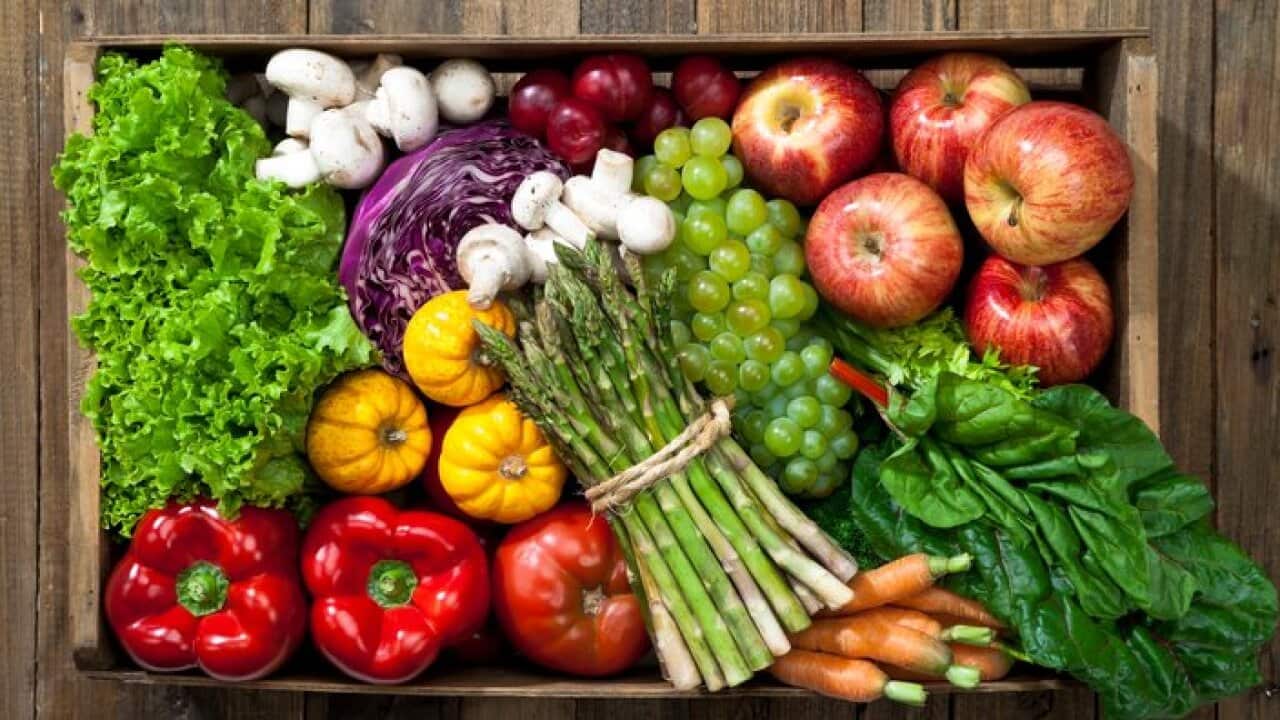 Crate full of fruits and vegetables over rustic table