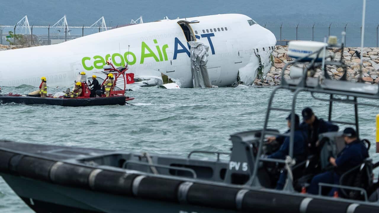 Rescue workers approach a partially submerged cargo aircraft that skidded off a runaway into the sea