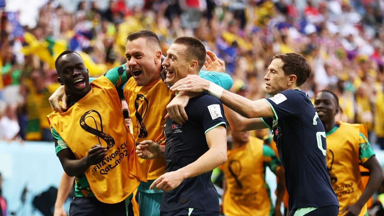 Teammates gather around Socceroos striker Mitch Duke after he scores the team's winning goal. 