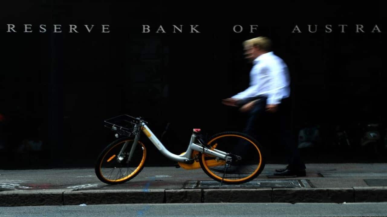 A man walks past a share bike that is in front of the RBA building.