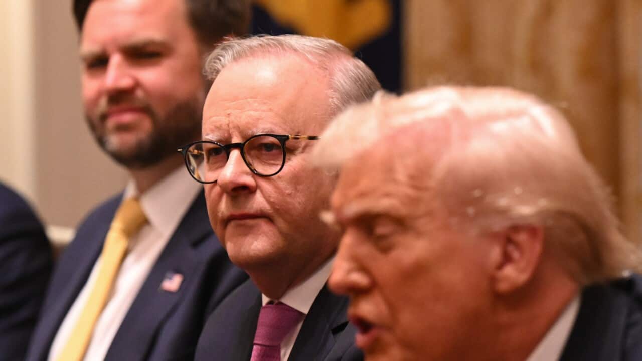 Three men sitting next to each other wearing suits
