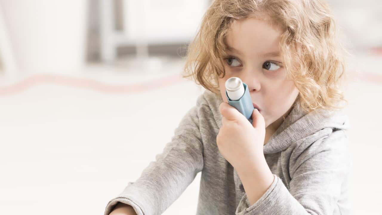 Small girl using inhaler device, playing with toys on a floor
