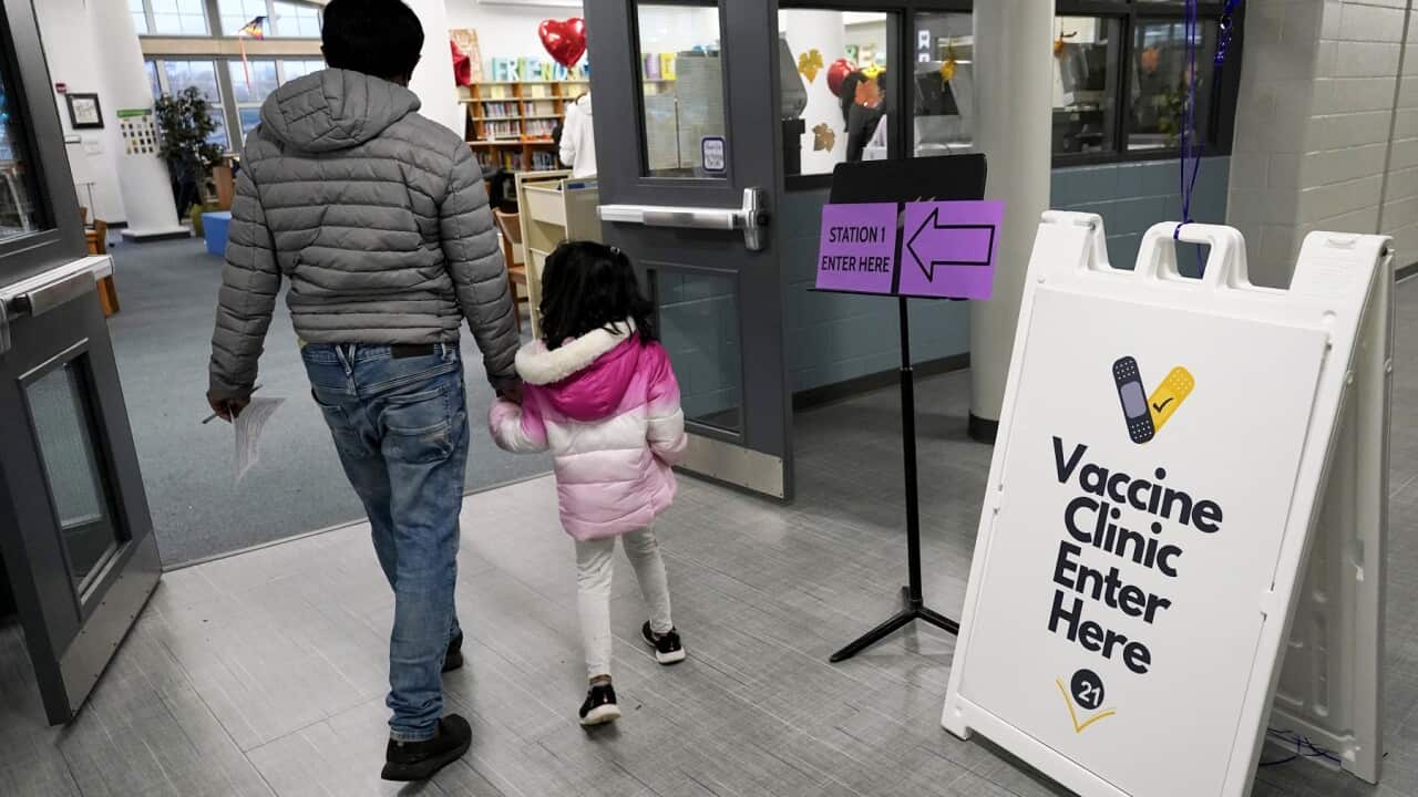 A child and her parent walk to take the Pfizer COVID-19 vaccine