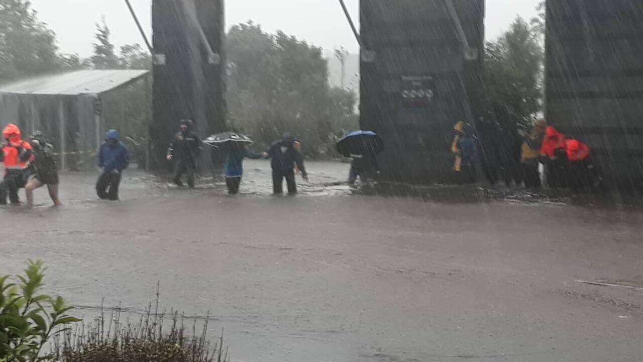 Groups of people seek higher ground as flood waters inundate the Milford Visitors' Terminal.