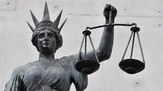 A grey statue of a woman holding scales and wearing a crown