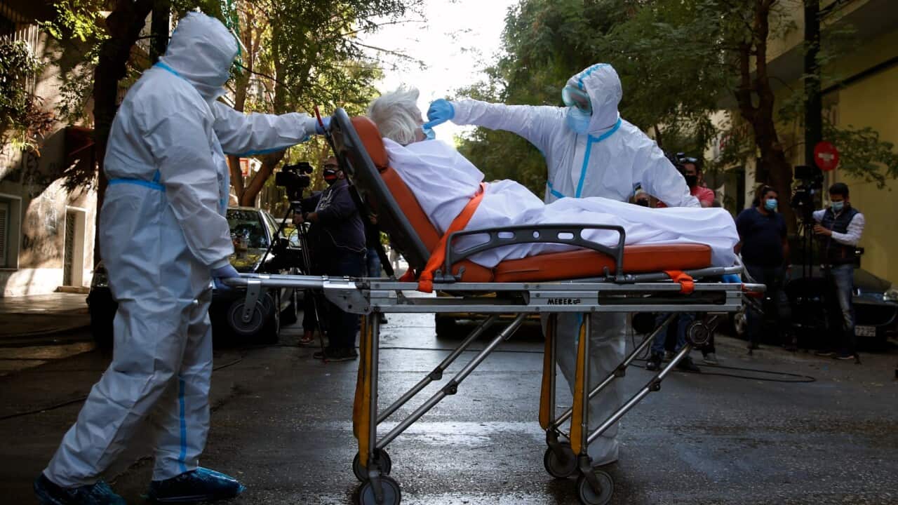 A paramedic with a special suit to protect against coronavirus, adjusts the face mask of a patient, 1 October 2020, Athens.