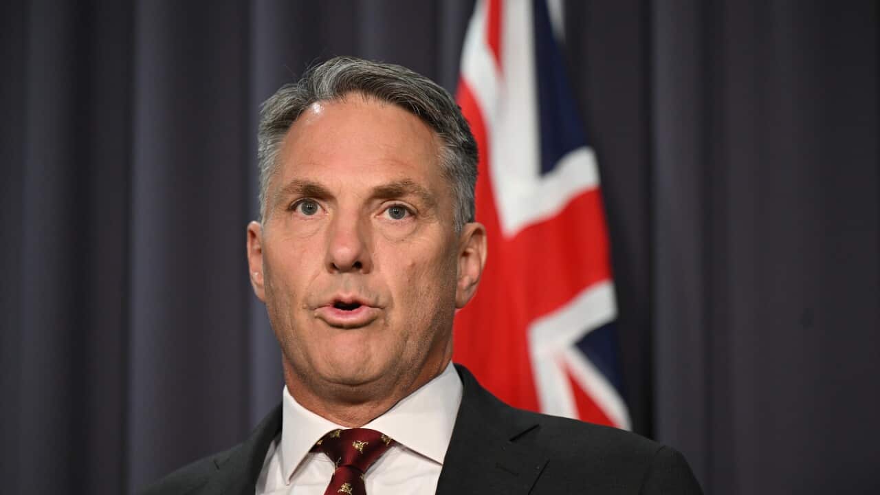 A man in a suit addresses the media