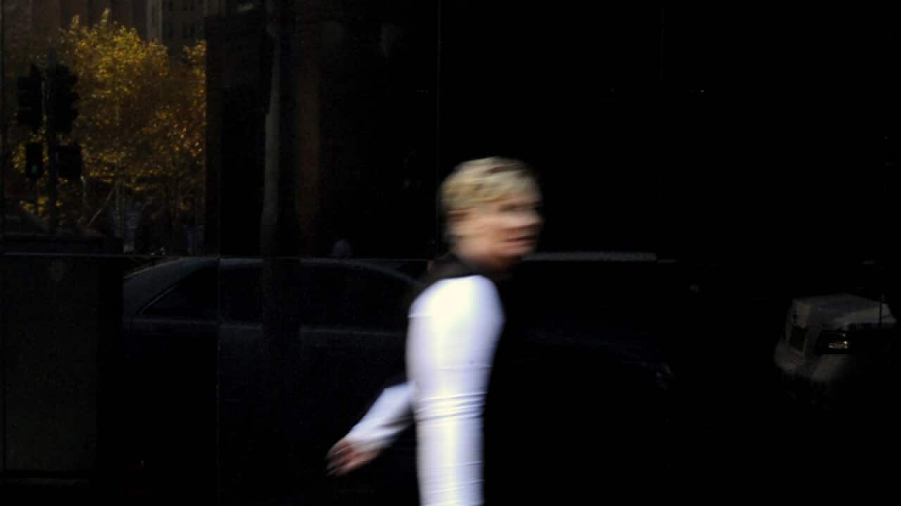 A pedestrian walking past the Reserve Bank of Australia in Sydney