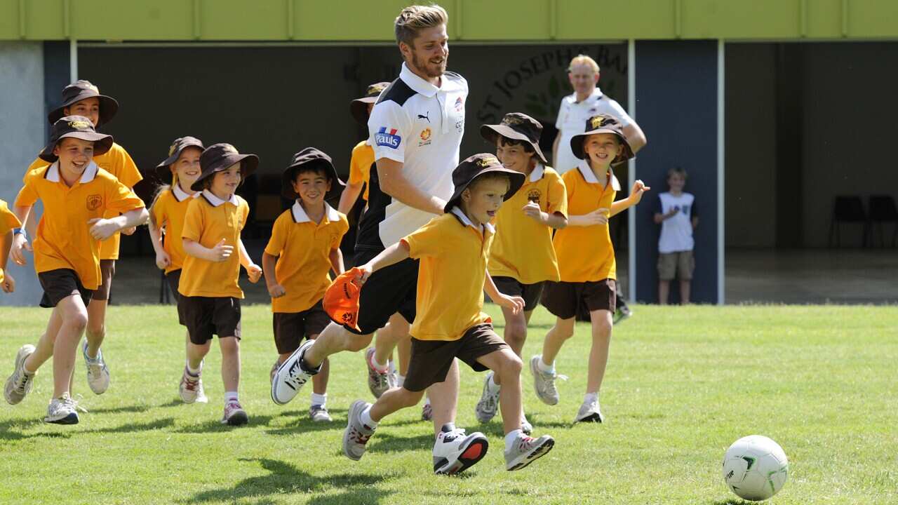 Brisbane Roar midfielder Luke Brattan plays with school children during a media event in Brisbane, Tuesday, April 22, 2014. (AAP/Dan Peled)