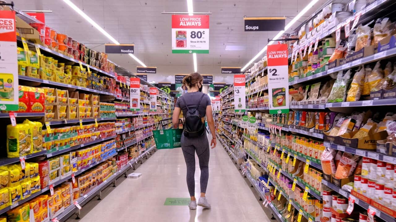 A woman walking down a supermarket aisle