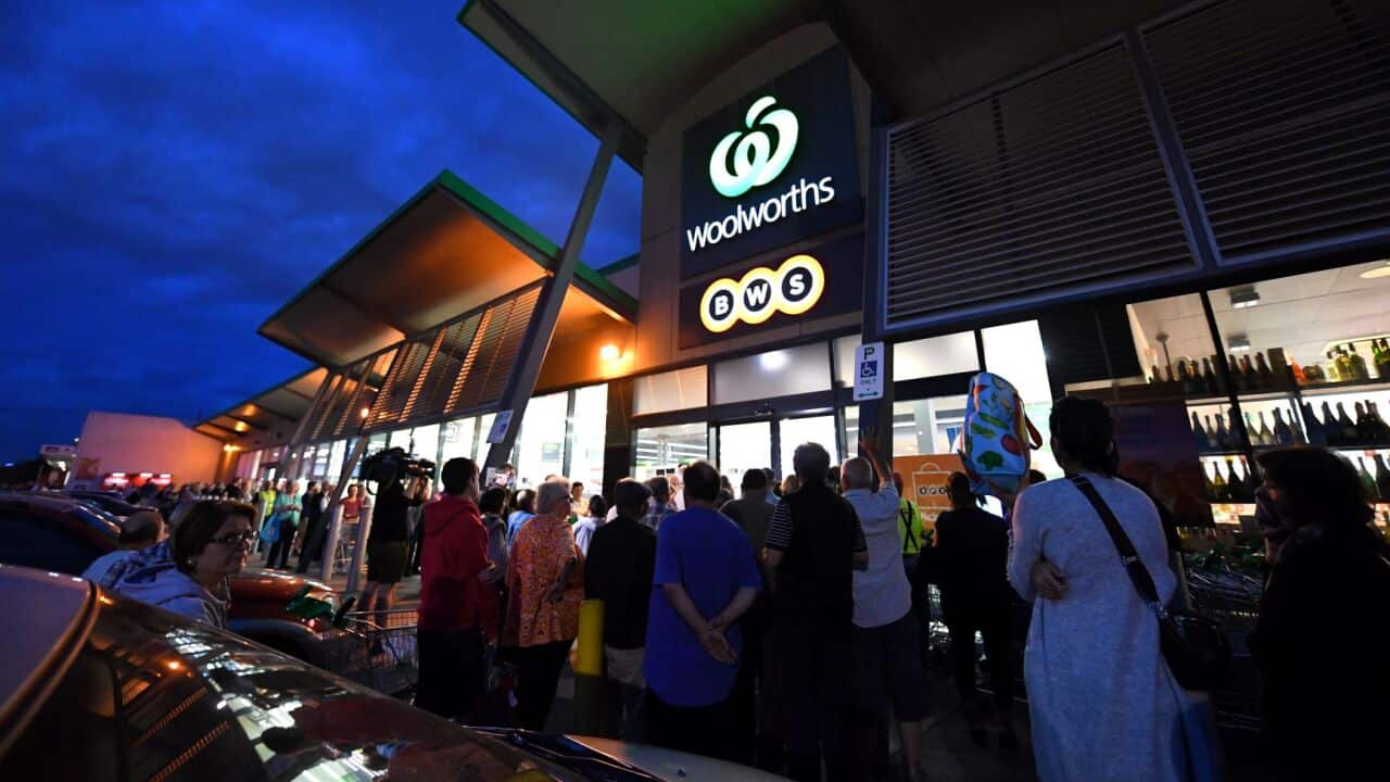 People are seen waiting outside a Woolworths supermarket in Coburg, Melbourne