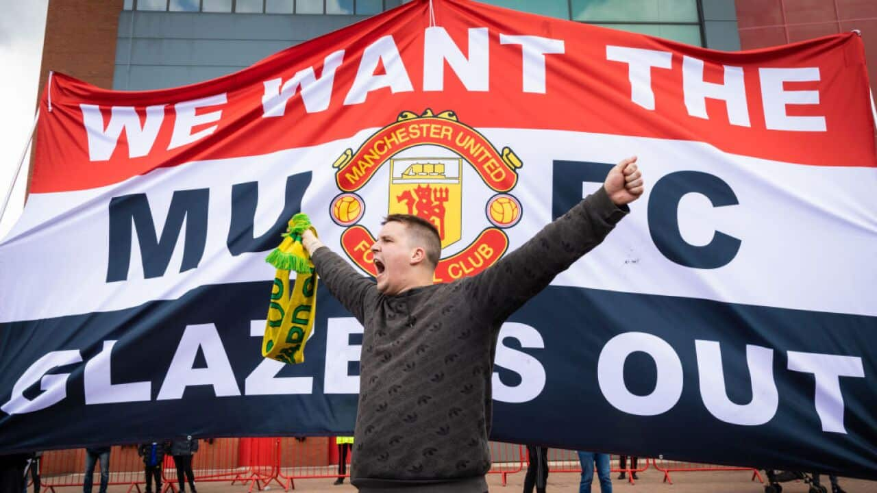 A football fan chants slogans in front of a banner before a