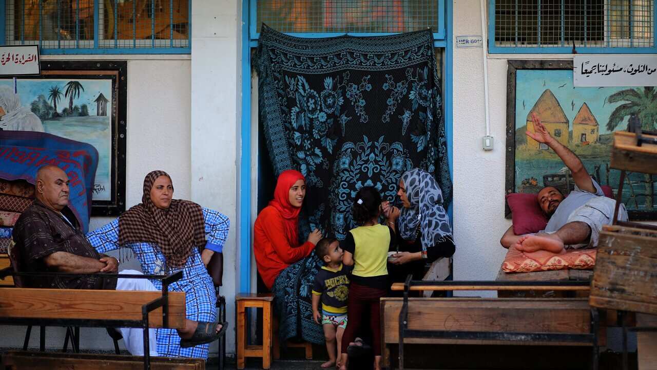 A Palestinian family sit outside the class room in the UN school in Jabalia, northern Gaza (AAP)