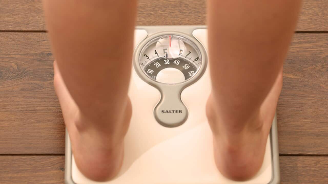 An 11 year old girl using a set of weighing scales