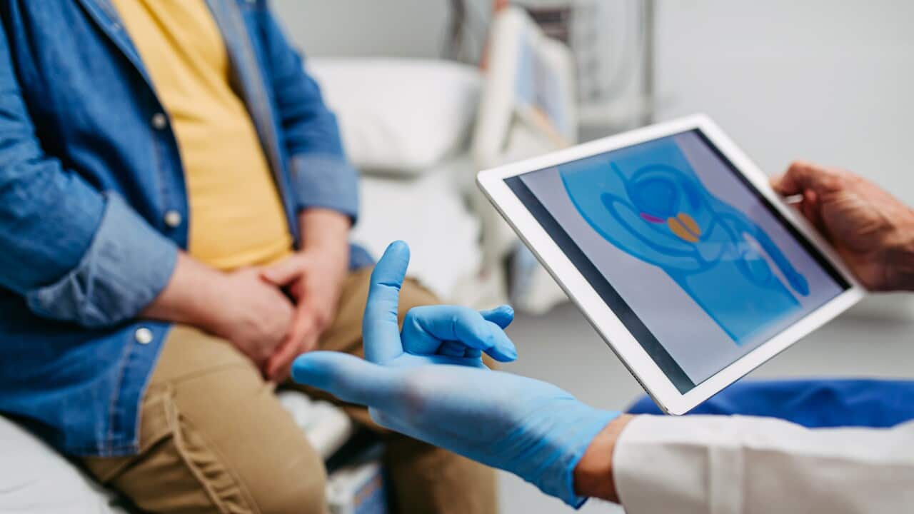 Doctor explaining prostate examination to male patient.