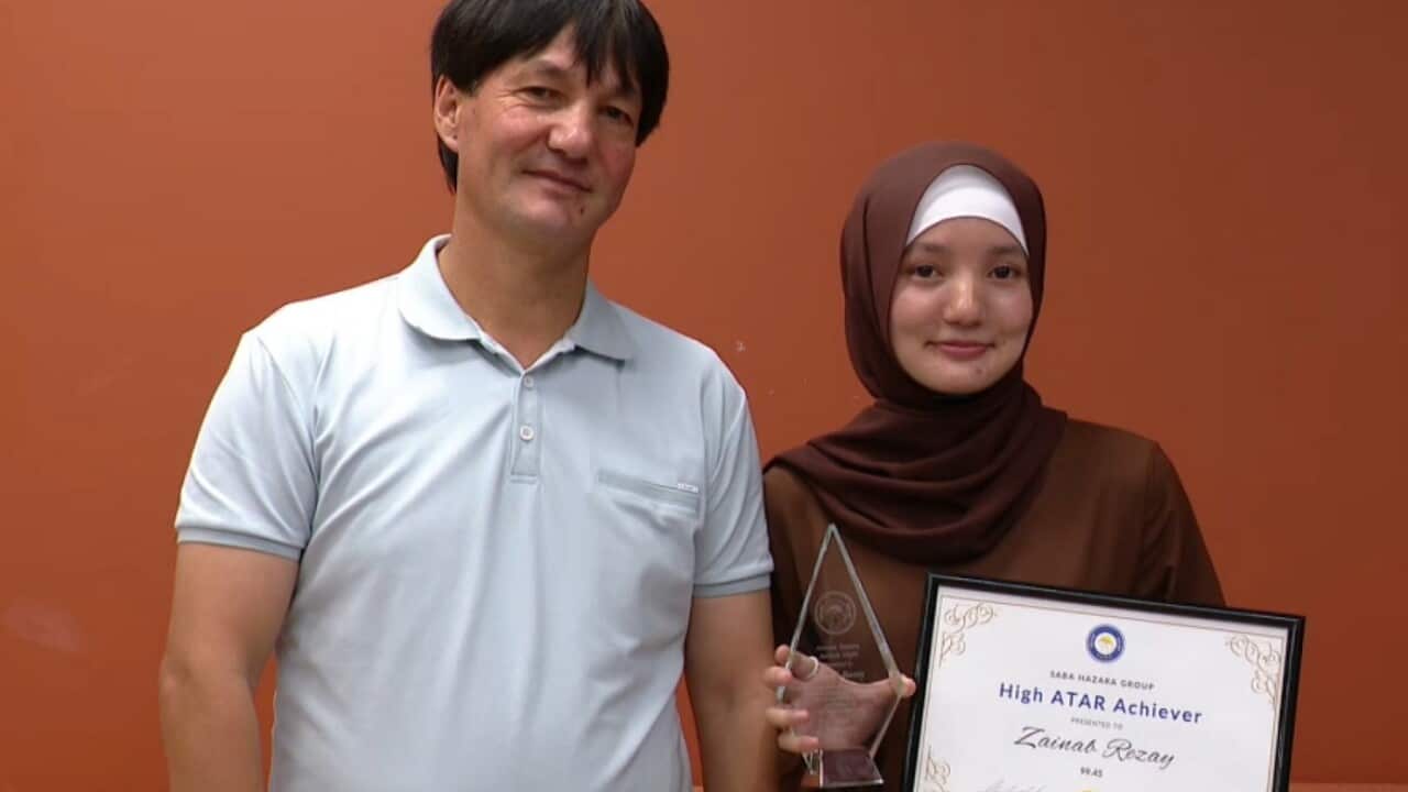 Zainab holding ATAR achievement award, standing next to her father.