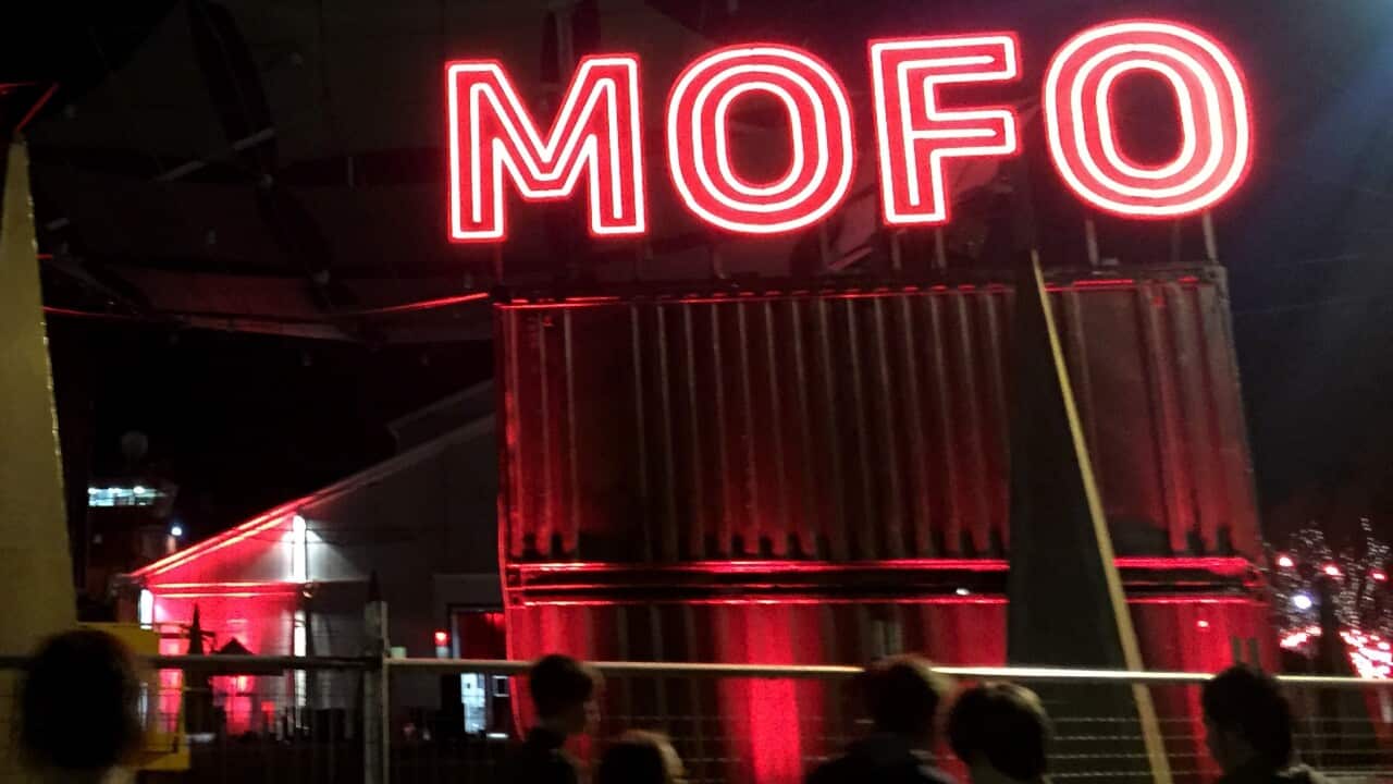 People walking beneath a sign that reads: "MOFO".