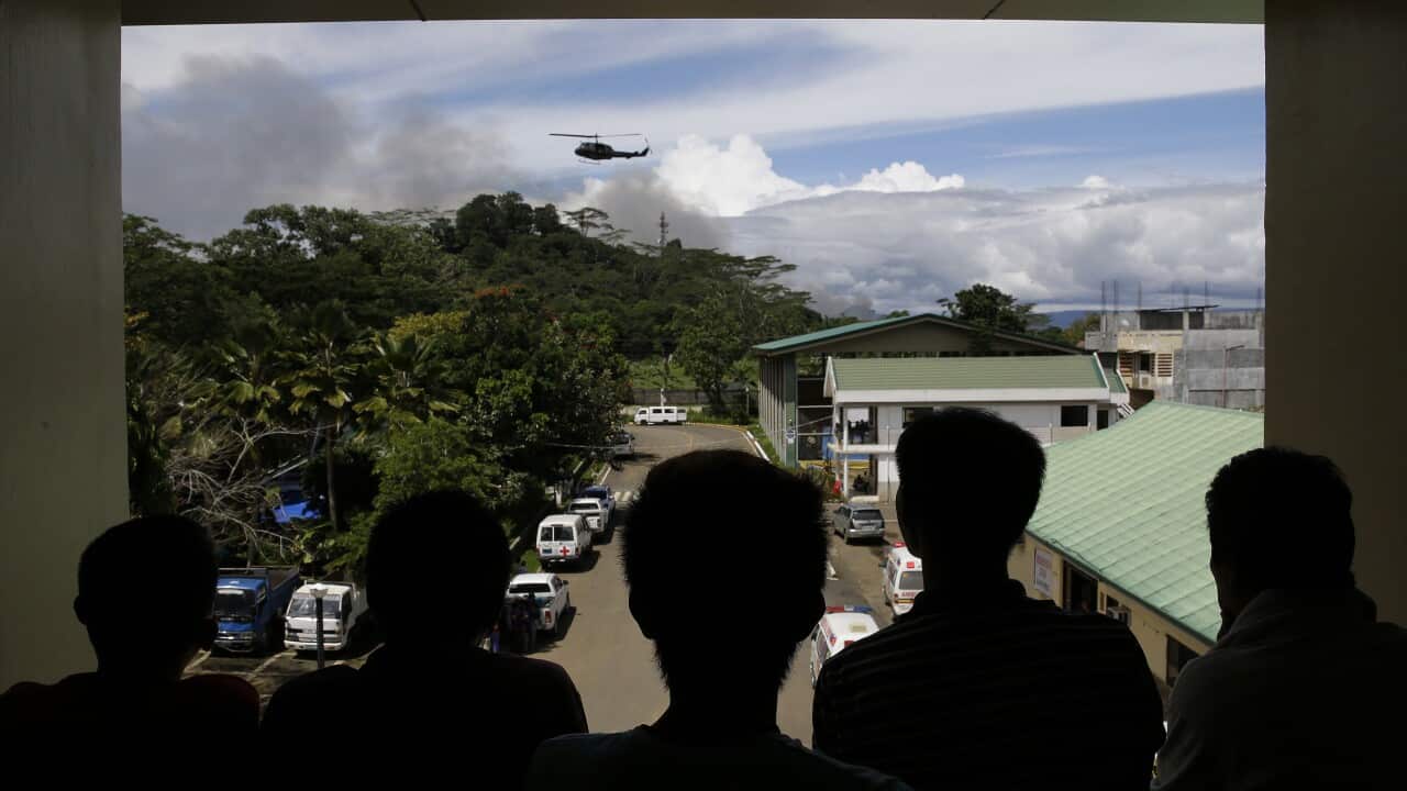 Evacuees look as a military helicopter passes by outside a temporary evacuation center in Marawi city, southern Philippines Friday, June 9, 2017.