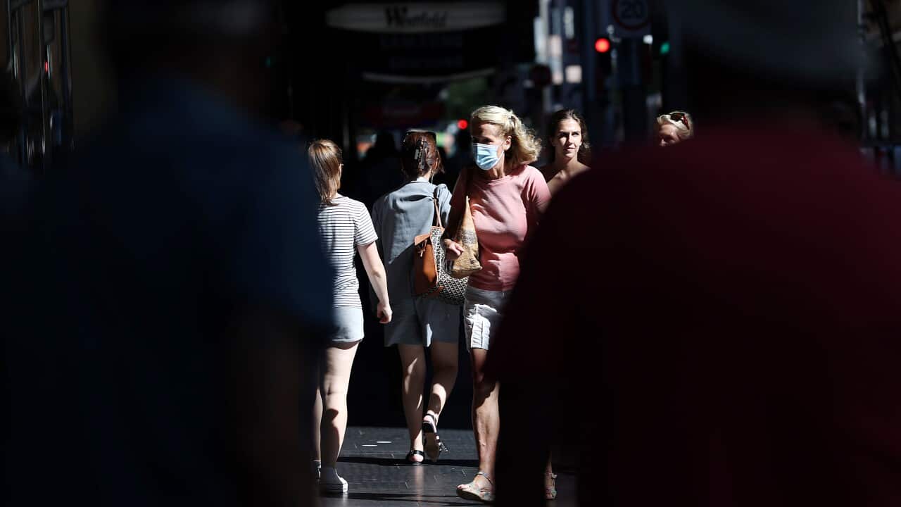 People walking along a footpath. One woman is wearing a face mask.