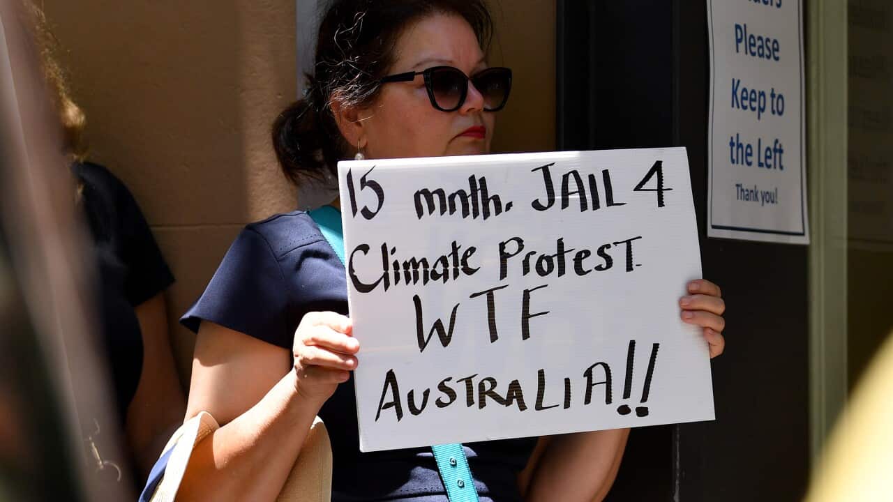 A woman holding a sign that reads: "15 months JAIL 4 Climate Protest. WTF Australia!!"