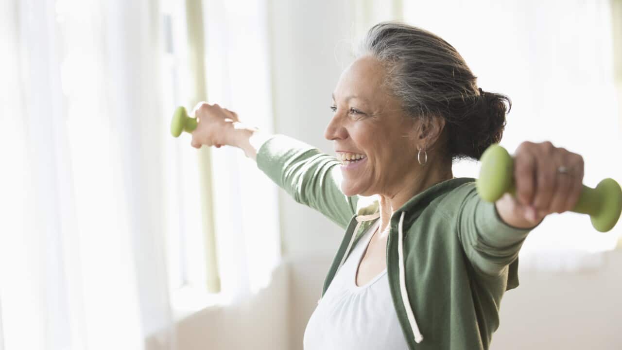 Older woman lifting weights in living room