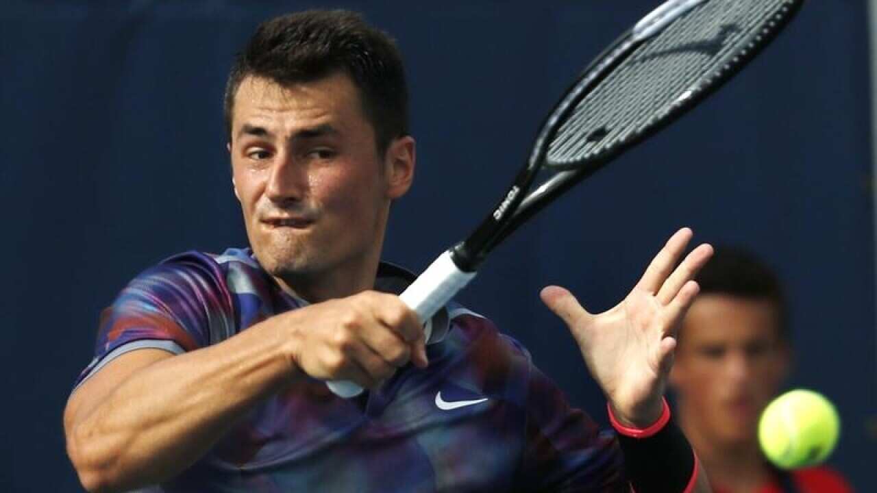 Bernard Tomic, of Australia returns a serve