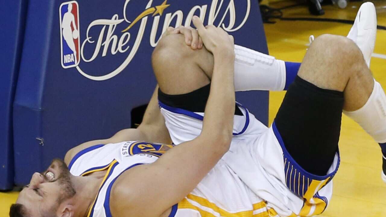 Andrew Bogut of Australia holds his knee in pain