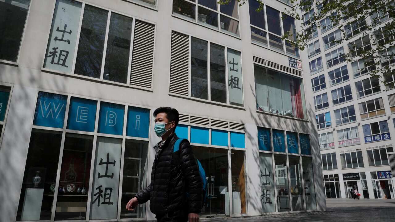 A man wearing a protective face mask walks by a vacant shop in Beijing.