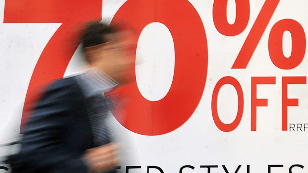 A pedestrian walks past retail signage
