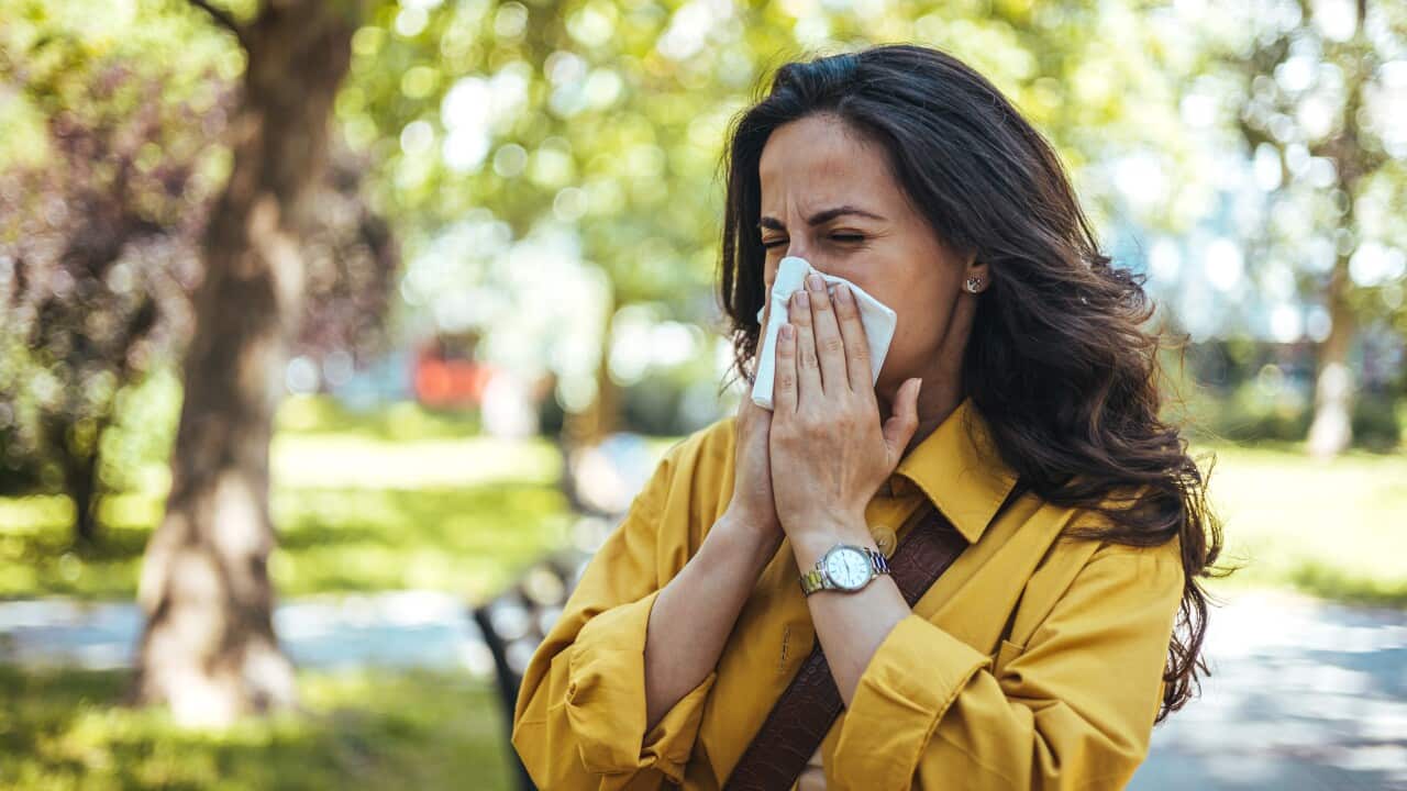 Portrait of female in yellow top with napkin blowing her nose