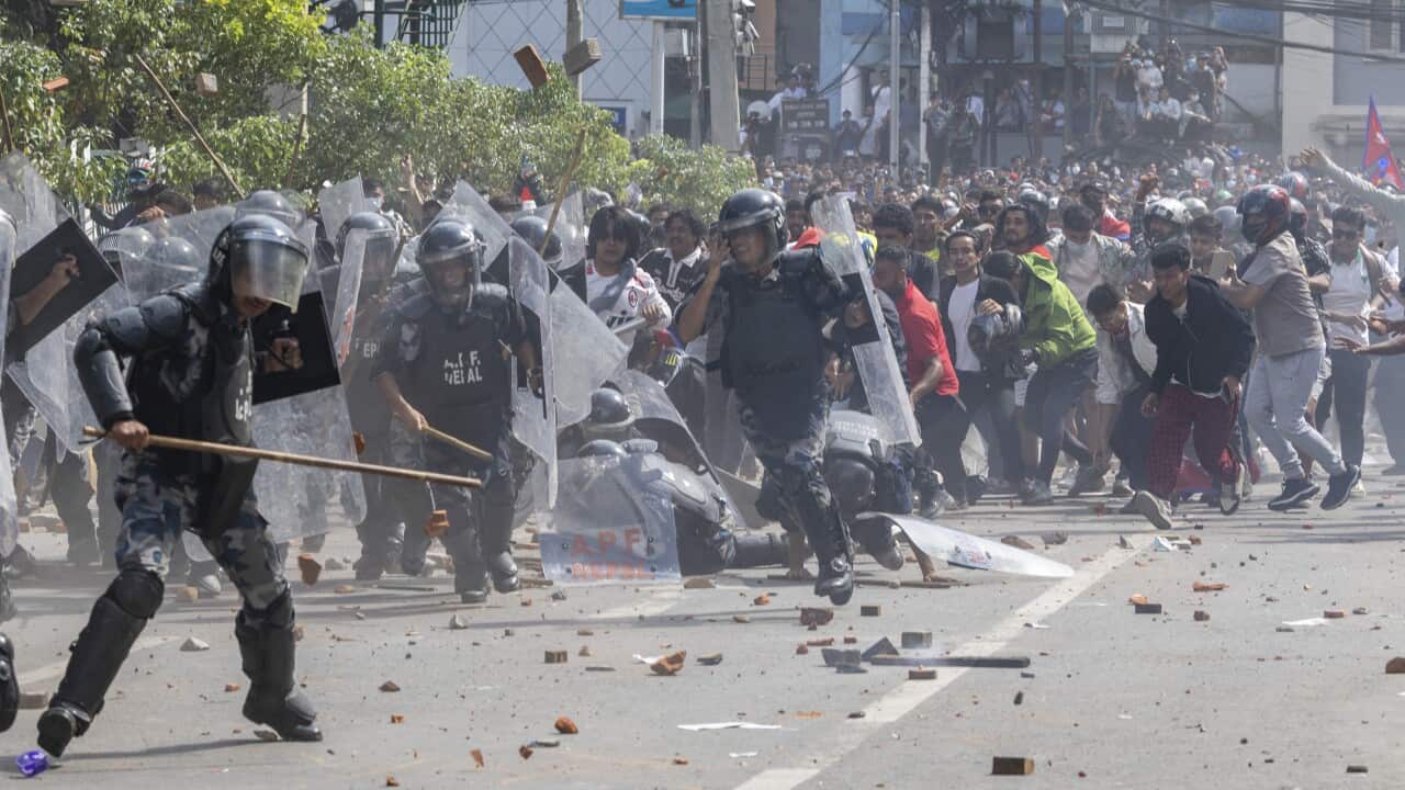 Police in riot gear clashing with protesters on a street.