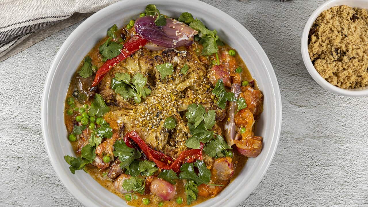 A white bowl holds a soupy vegetable mix. A small bowl of cooked grains sits to one side.