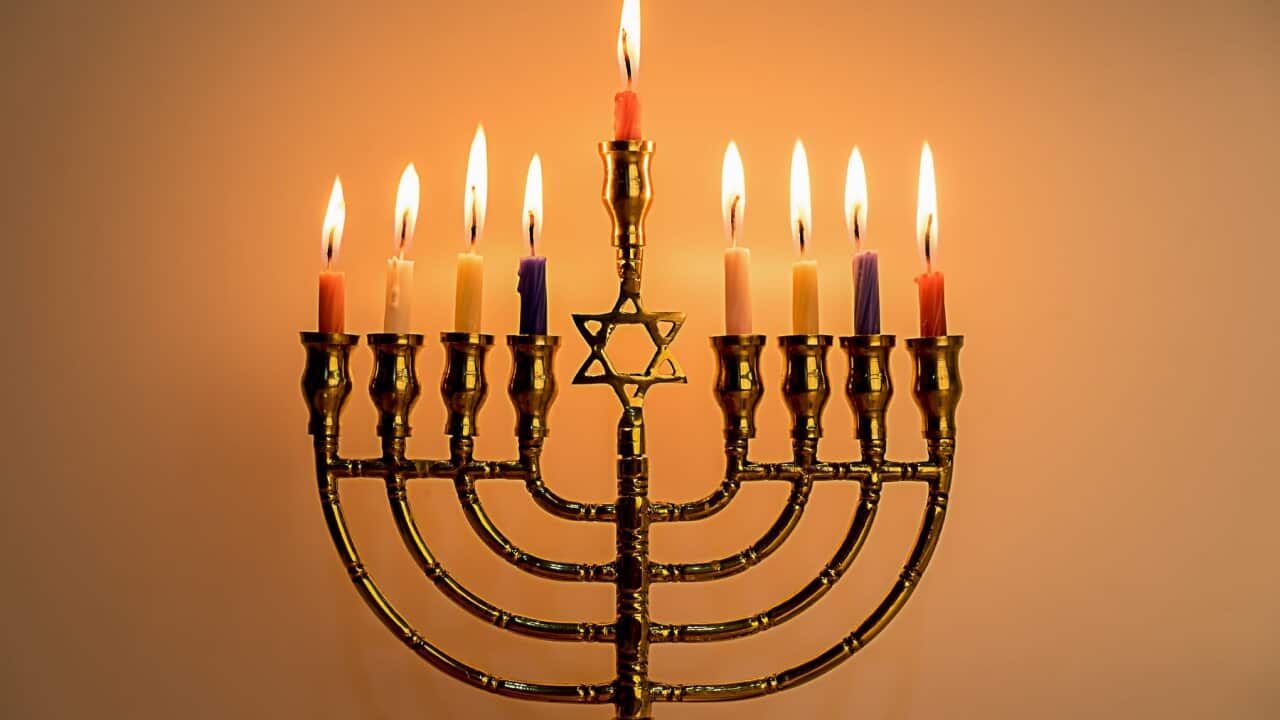 Illuminated Candles On Menorah Against Wall