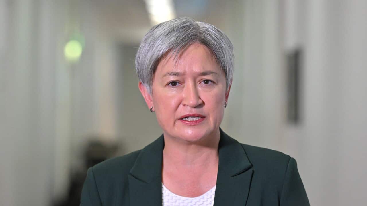 A woman wearing a suit holding a media briefing