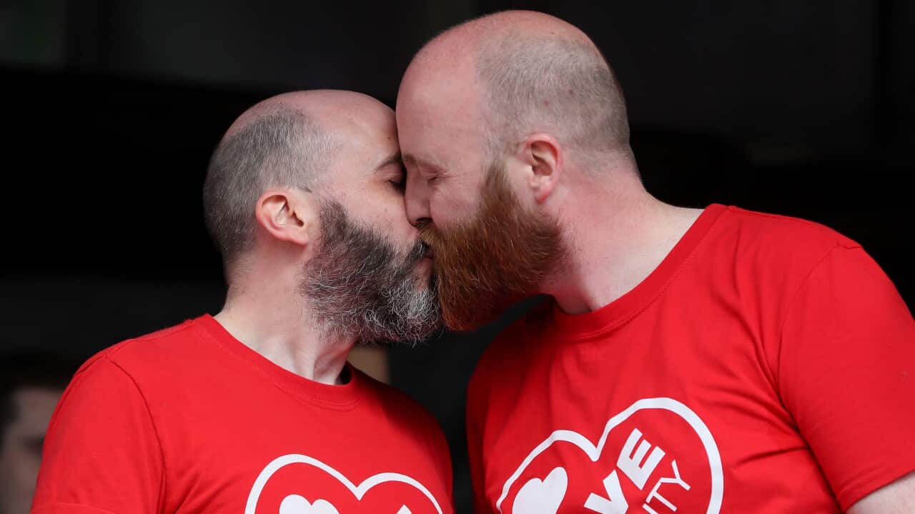 Rainbow Project director John O'Doherty and his partner on stage during a same-sex marriage march in Belfast.
